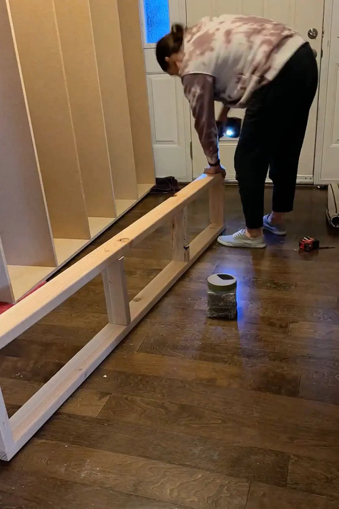 Constructing a wooden support base with 2x4s to elevate and stabilize a built-in mudroom locker storage system before installation.